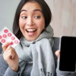 Woman taking medication while using a phone for STD clinic in Jacksonville information.