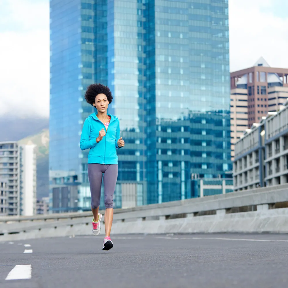 Woman jogging outdoors as part of a healthy lifestyle supported by wellness physicals.