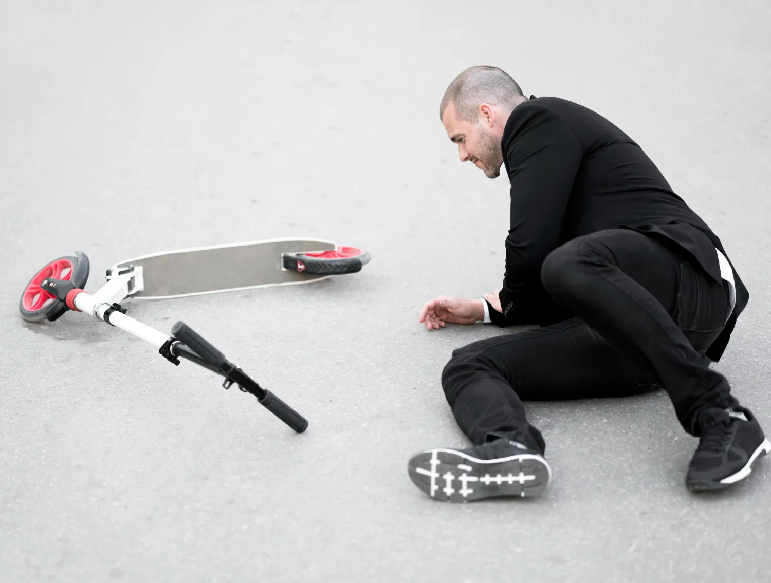 Person sitting on the ground after a slip and fall from a scooter, representing common injury risks, accident assessment, and personal injury treatment services