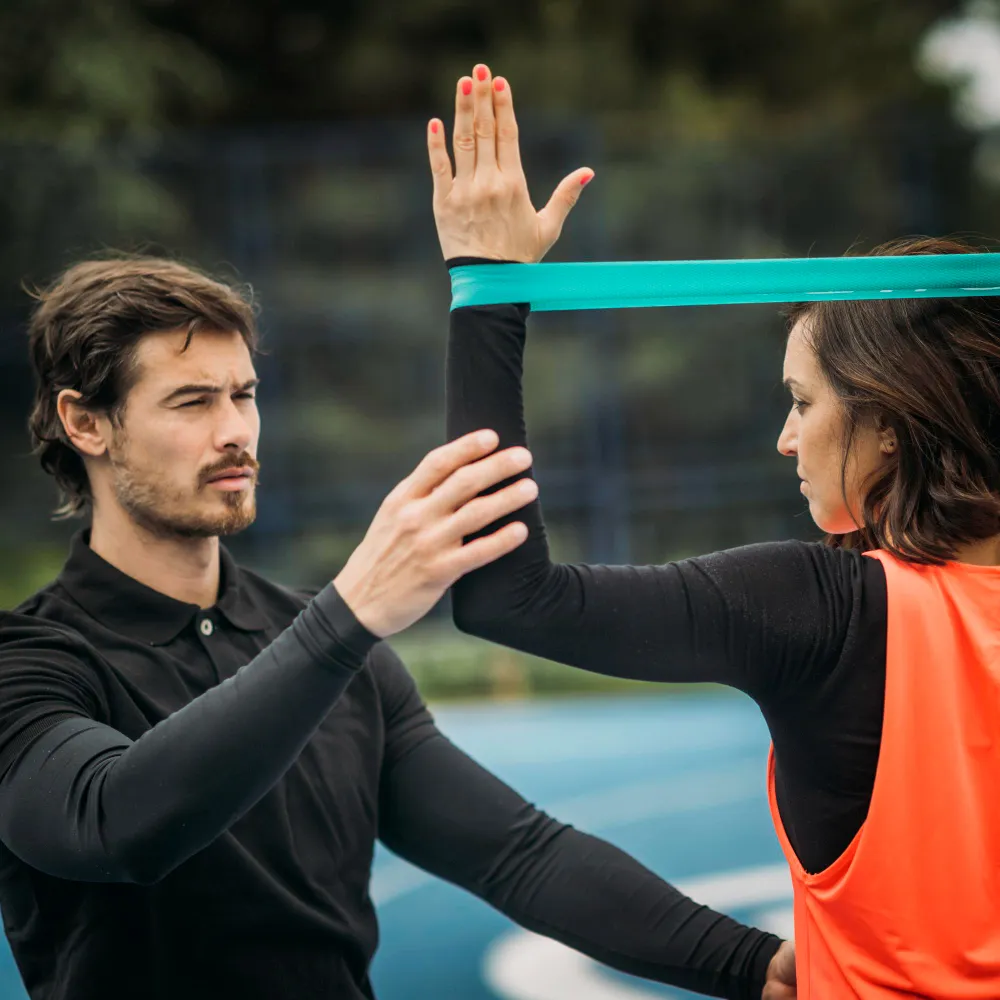 A fitness trainer assisting with resistance band exercises, highlighting personalized care and services offered at a wellness center in Jacksonville focused on preventive health and physical well-being