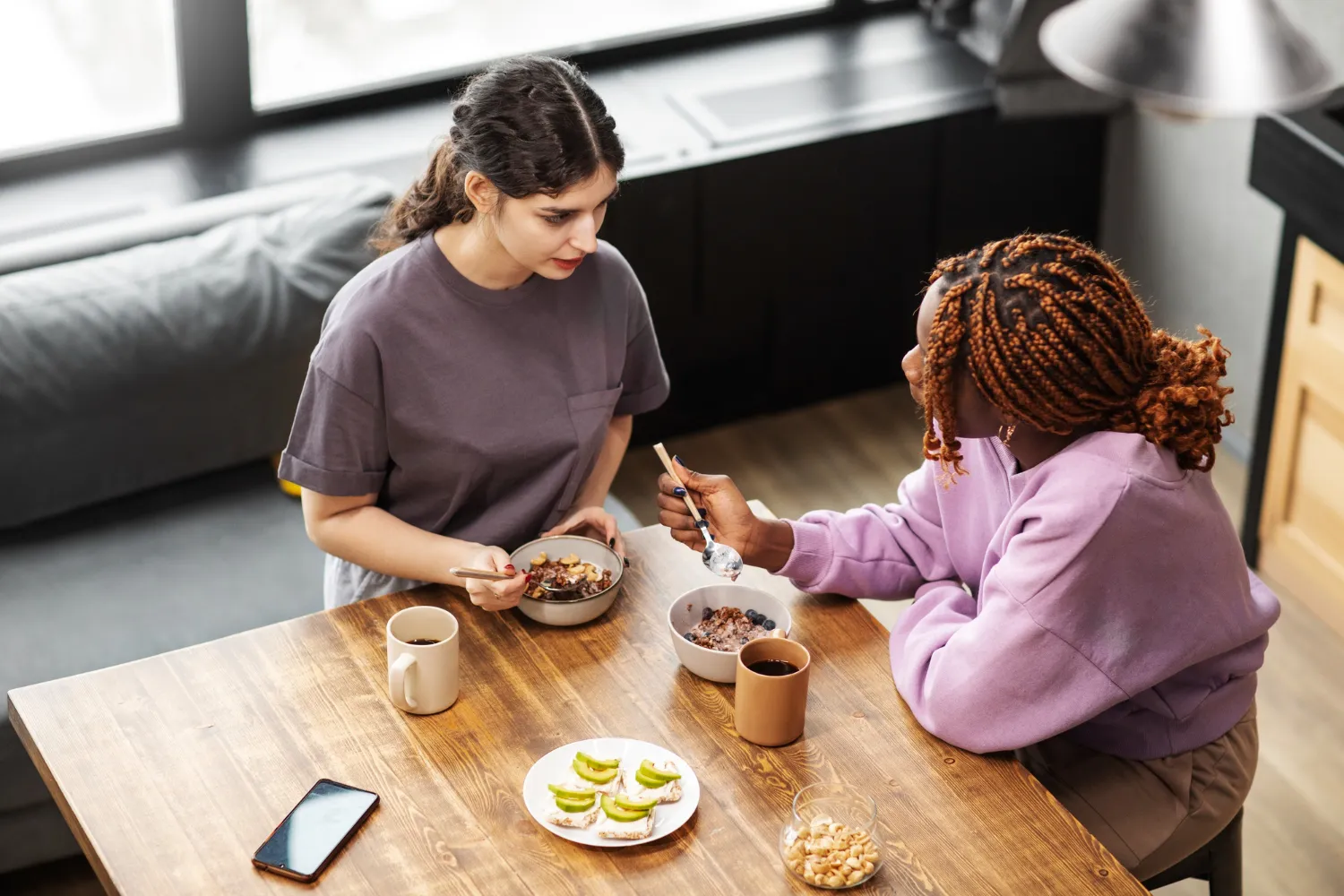 Two individuals sharing a meal and having a supportive conversation, representing recovery support and professional care at an eating disorder clinic