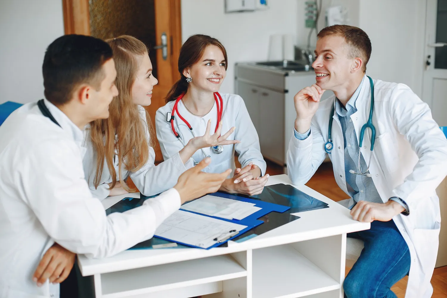 Family medicine physicians and internal medicine physician discussing patient reports and treatment plans in medical office