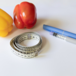 GLP-1 weight loss concept with measuring tape, healthy vegetables, and semaglutide injection pen for medical fat loss