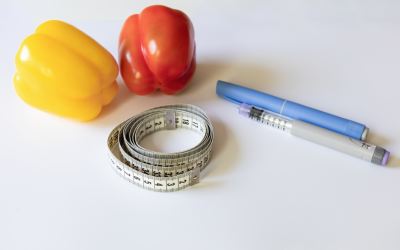 GLP-1 weight loss concept with measuring tape, healthy vegetables, and semaglutide injection pen for medical fat loss