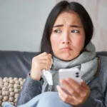 Woman feeling sick at home checking phone for womens primary care services and female primary care doctor near me