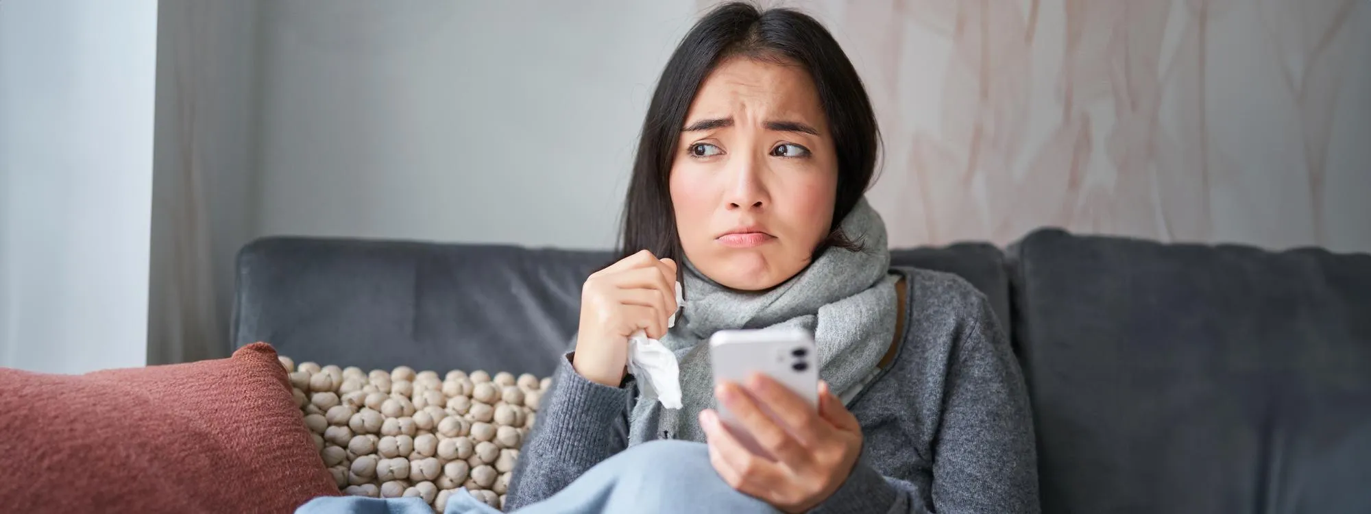 Woman feeling sick at home checking phone for womens primary care services and female primary care doctor near me