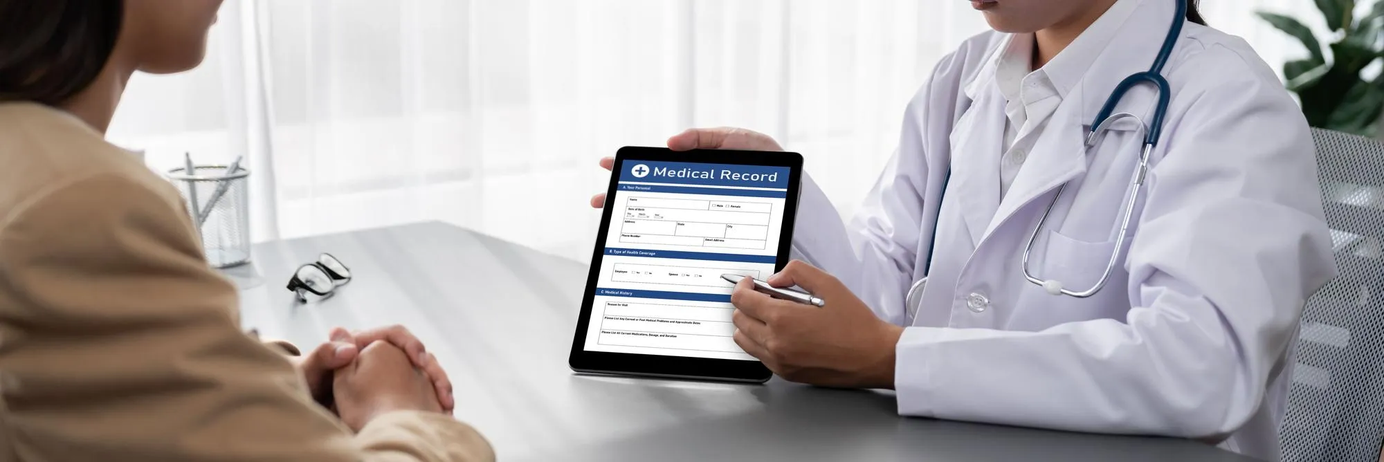 Primary care clinic physician reviewing digital medical records with patient during healthcare consultation