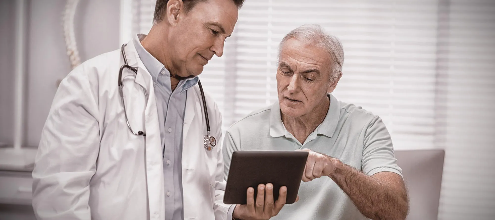 Doctor reviewing health information on a tablet with an older male patient to discuss screening options and testosterone replacement therapy Jacksonville.