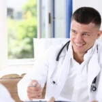 A male doctor discussing health concerns with a patient during a consultation, representing professional guidance from a Men's Health Specialist and support for men's wellness.